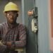 man in blue white and red plaid button up shirt wearing yellow hard hat holding black