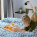 woman lying on bed white holding board