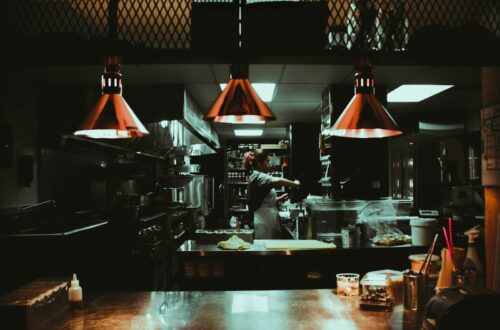 woman standing near three red pendant lamps